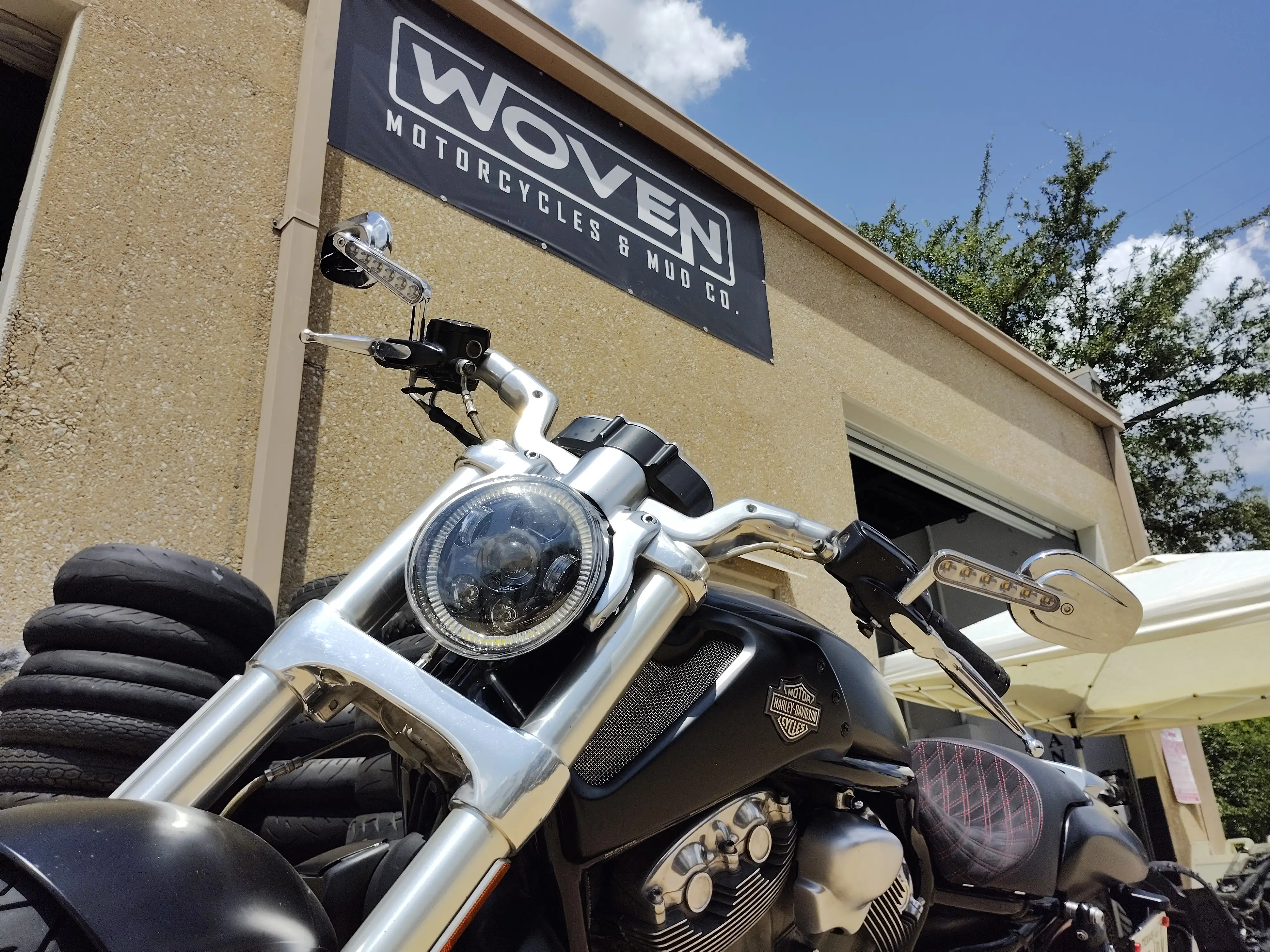 Motorcycle parked beneath the Woven storefront sign