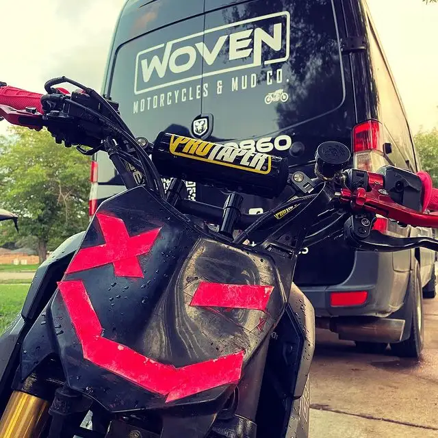 Two mechanics working on a motorcycle in a van